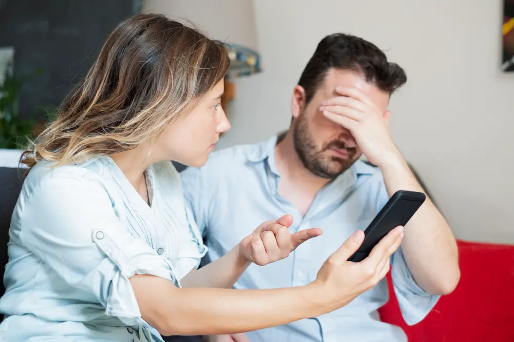 woman finding proof of cheating on partners phone with man looking upset