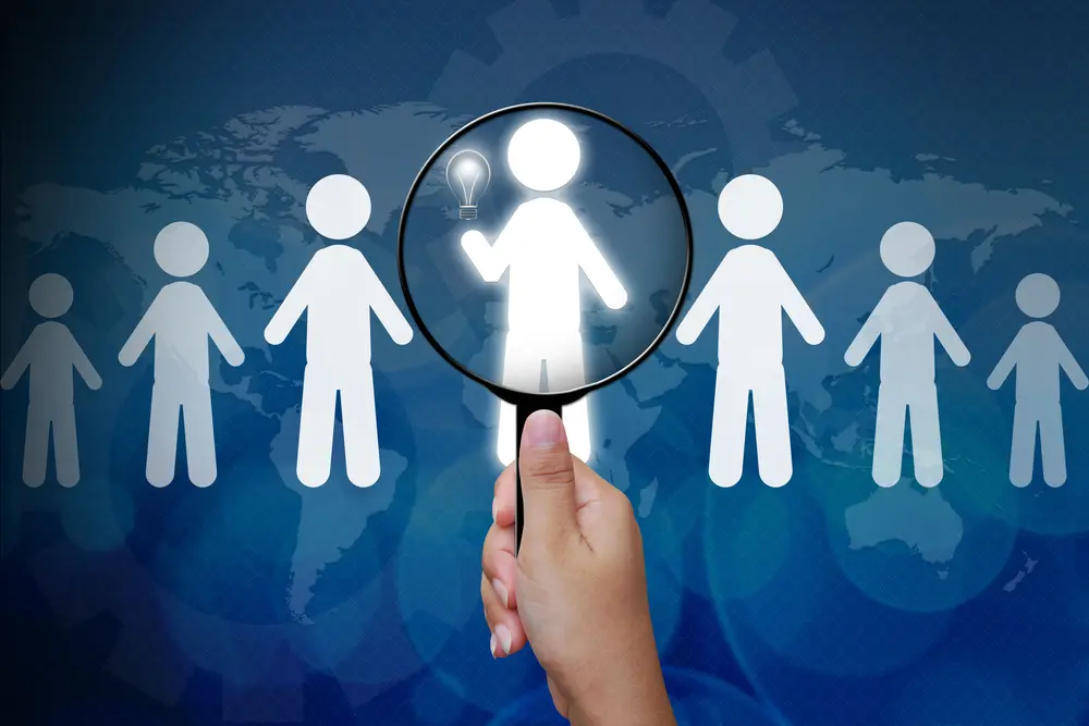 person with magnifying glass over graphic of people across the world