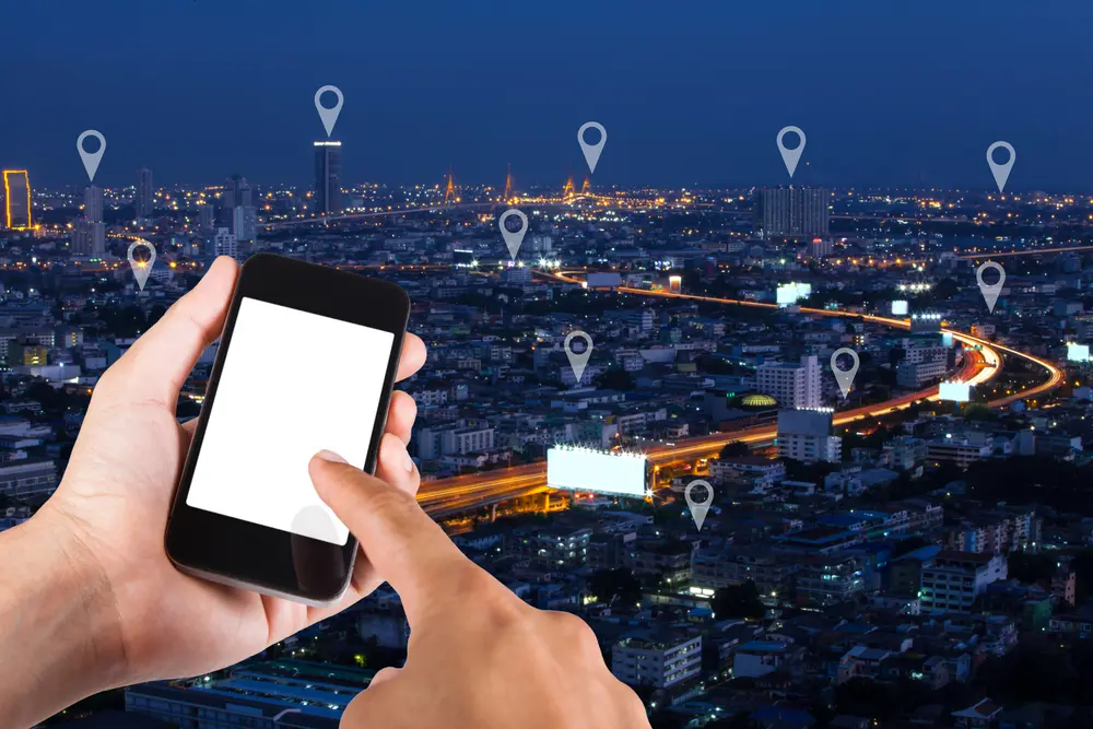 person pointing at phone looking for location with cityscape in the background